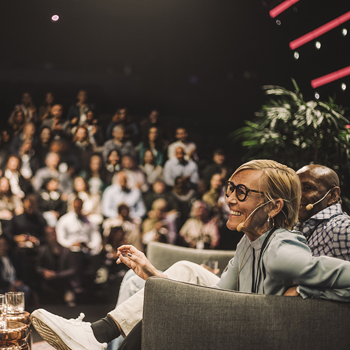 Interviewer interacting with smiling entrepreneurs during panel discussion at conference event