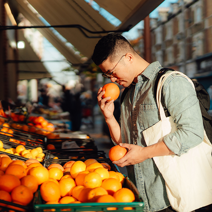 Young Asian man shopping fresh fruits at street market