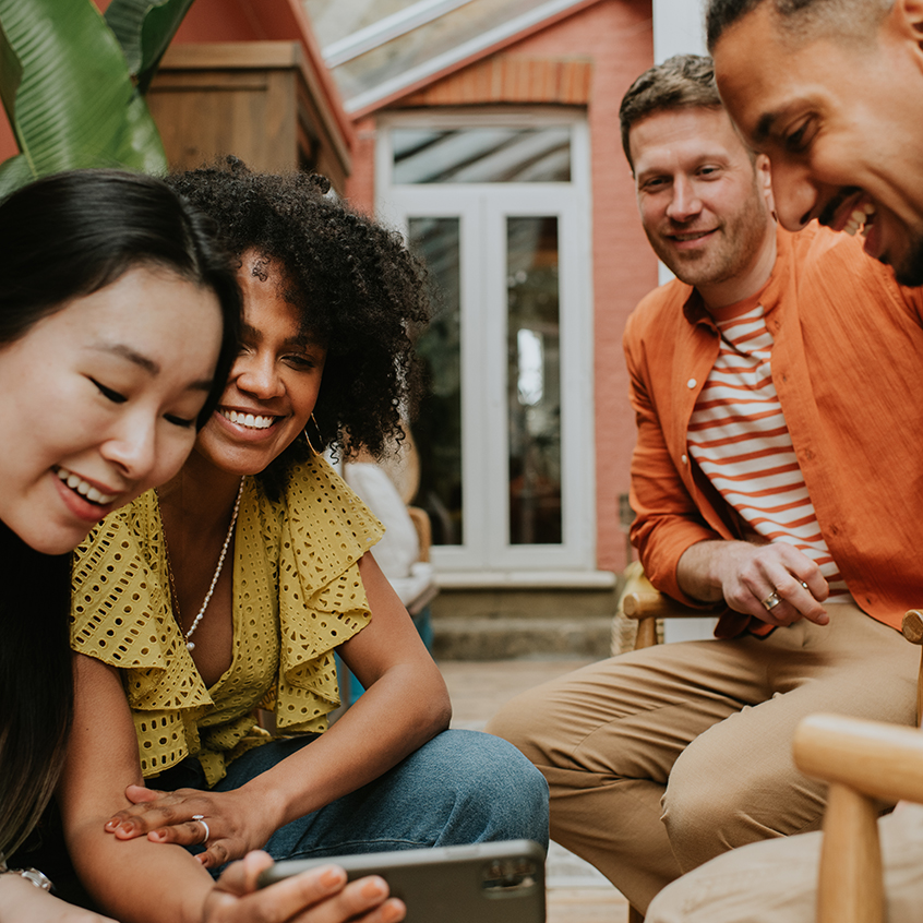 A group of 4 young people watch a video on a smart phone