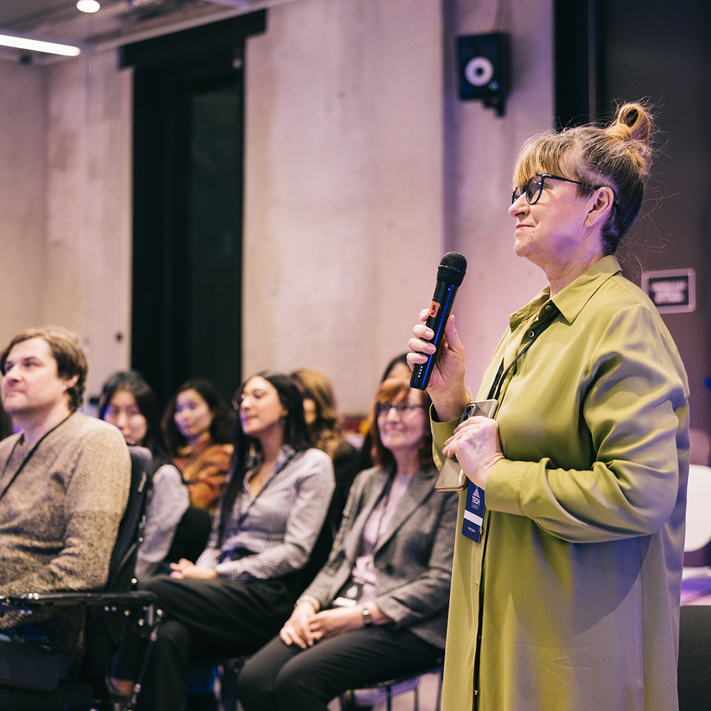 Businesswoman asking a question from a entrepreneur on conference stage