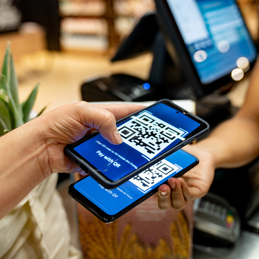 Woman at the supermarket scanning a code to make a mobile payment