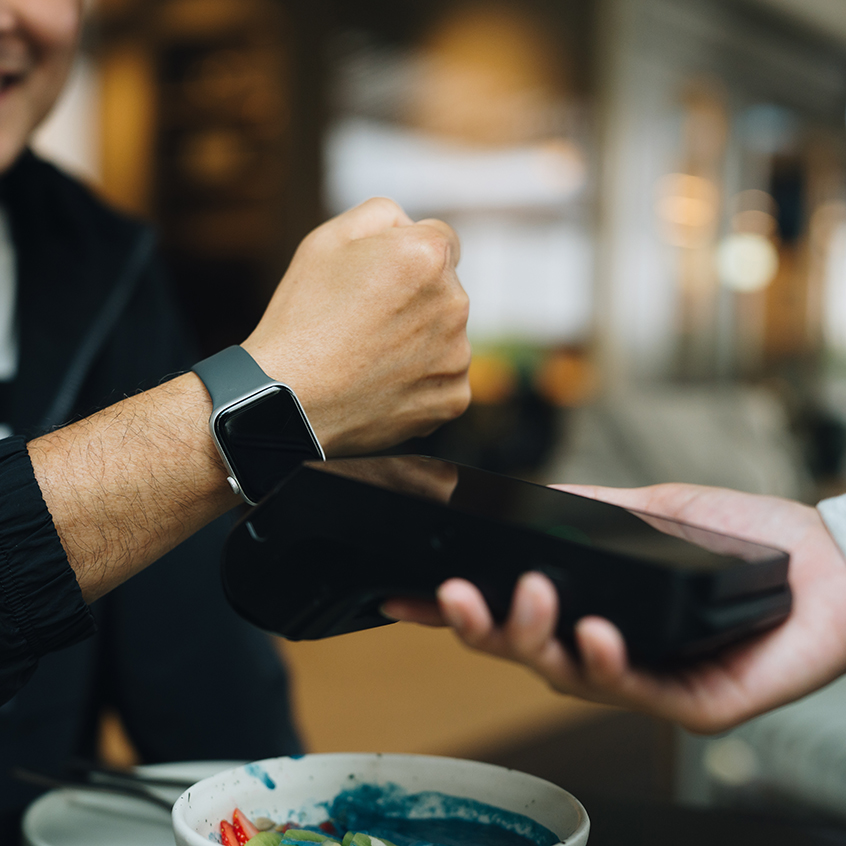 Close-up shot of man using a smart watch to make a contactless payment at an organic healthy restaurant