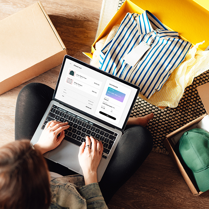Young woman doing online shopping with laptop sitting on the floor at home