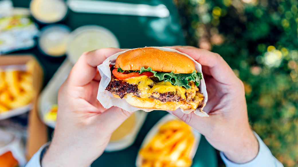 Man eating juicy cheeseburger, personal perspective view