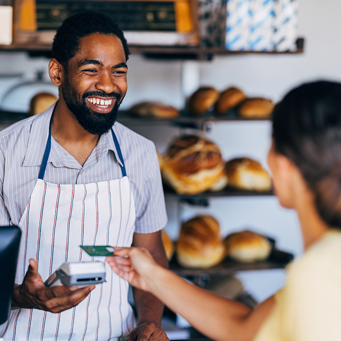 Smiling Baker Accepting Payment from Customer in Bakery