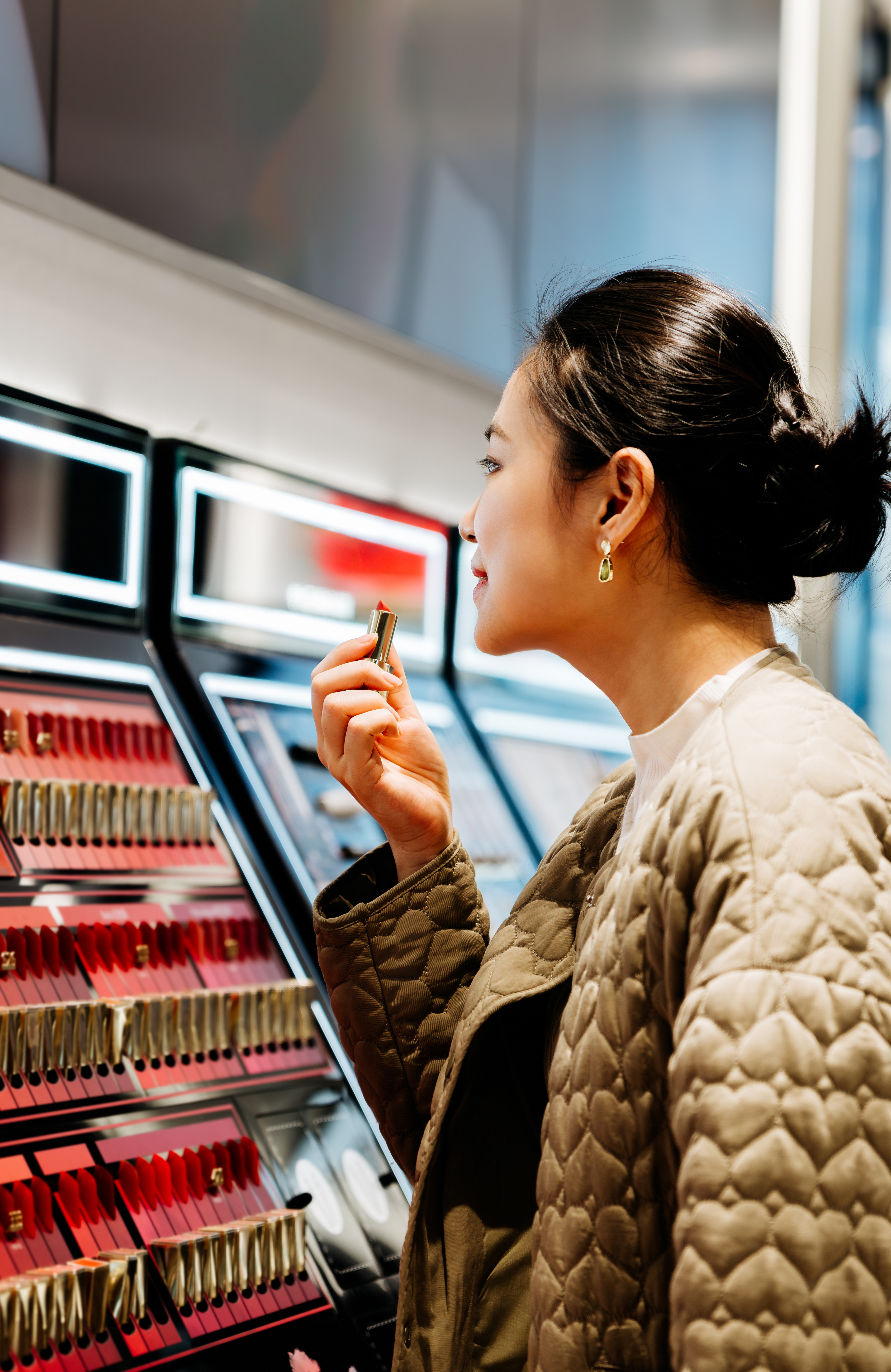 Asian beautiful women trying on lipsticks while shopping makeup products at beauty store.